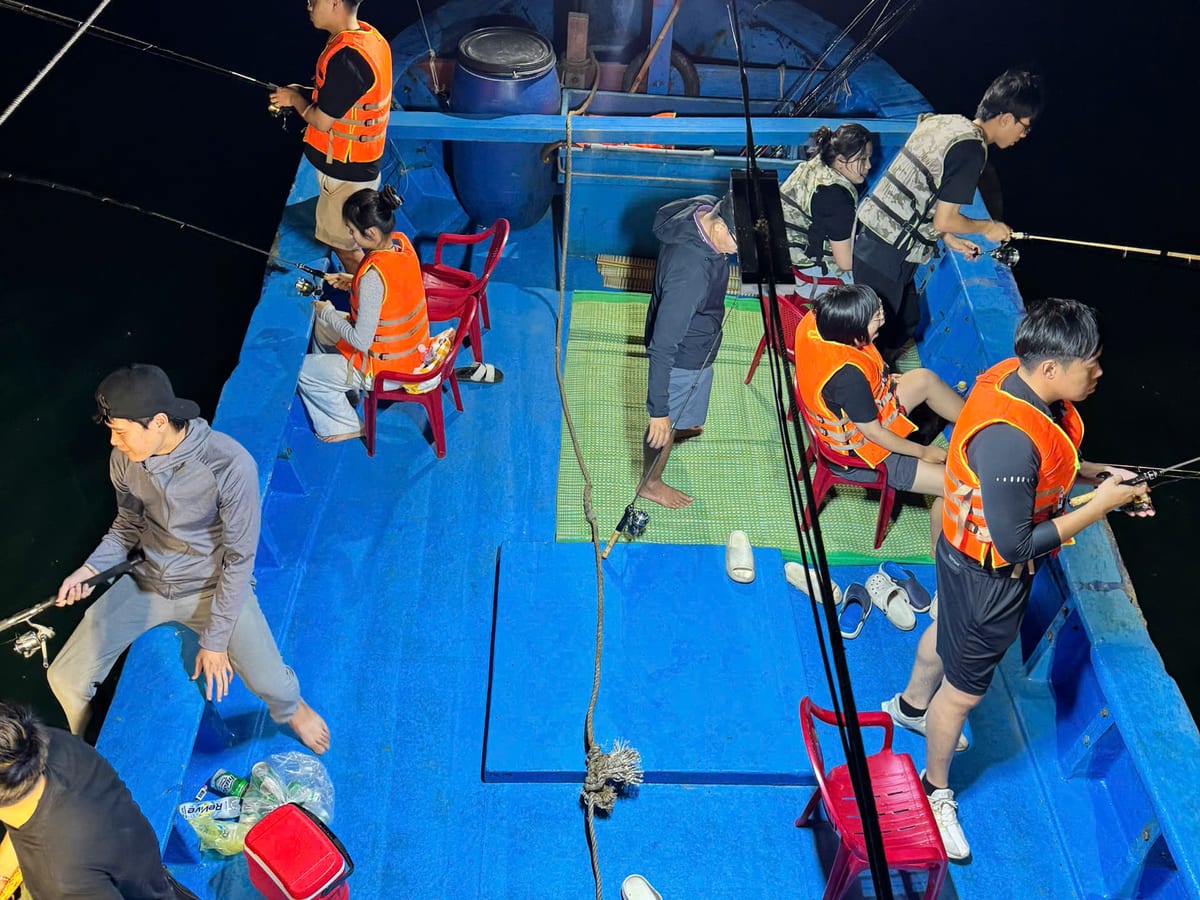 Guests squid fishing along the rail under the boat floodlights at night off Phu Quoc